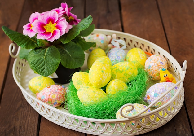 Oeufs de Pâques et fleurs sur une table en bois sombre