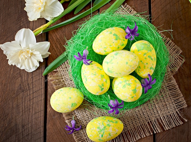 Oeufs de Pâques et fleurs sur table en bois