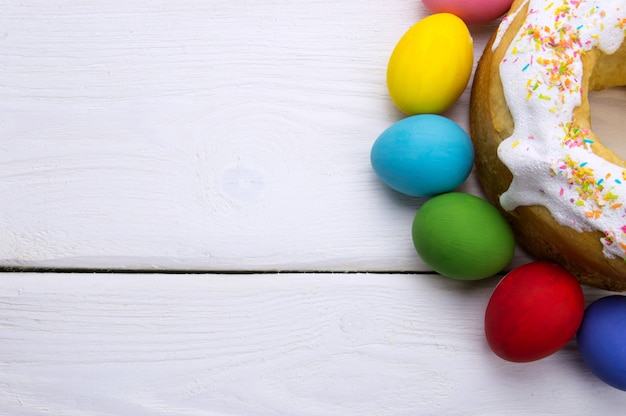 Oeufs de Pâques et gâteau de Pâques sur une surface en bois blanche