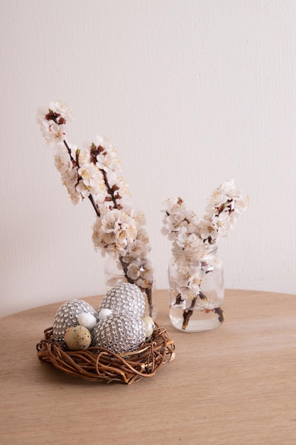 Oeufs de Pâques glamour dans un nid de fleurs. Décorations de table minimalistes à la maison pour les vacances de printemps.