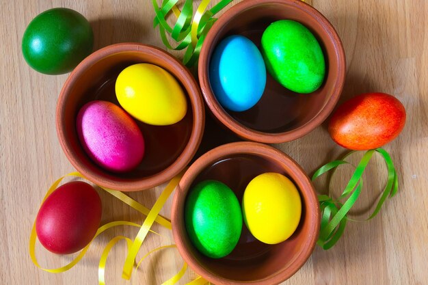 Des œufs de Pâques en gros plan de couleurs vives dans des bols d'argile à l'arrière-plan des fêtes