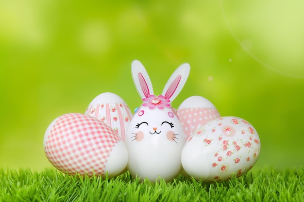 Oeufs de Pâques sur l'herbe Oeuf de lapin et oeufs décorés de rose sur fond de bokeh vert printemps Joyeuses Pâques composition