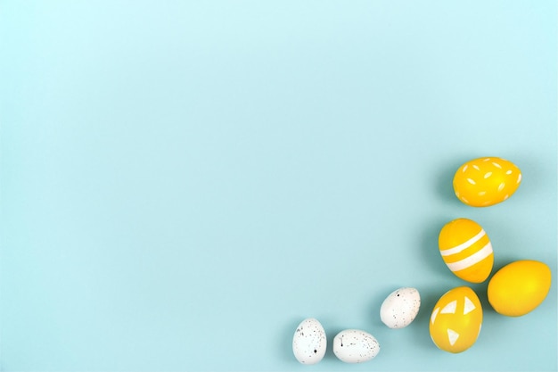 Photo des œufs de pâques en jaune et blanc sur un fond bleu pastel à plat