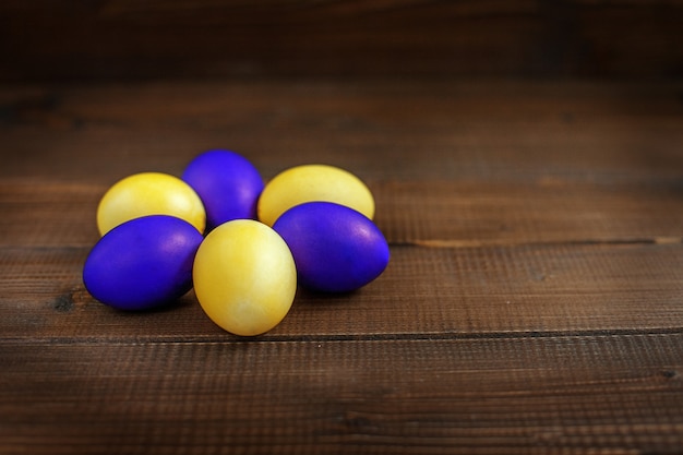 Oeufs de Pâques jaunes et violets sur une table en bois. Le concept de vacances et de joyeuses Pâques