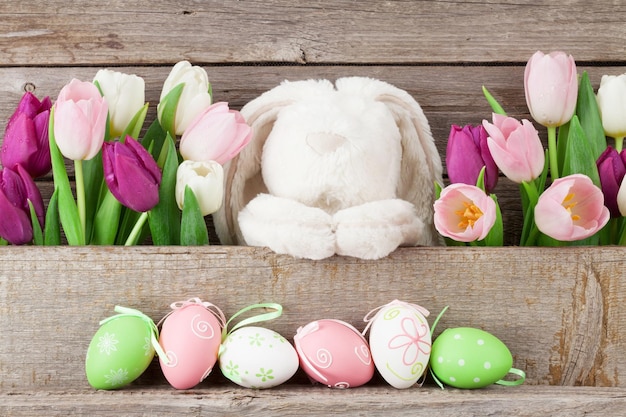 Oeufs de Pâques lapin jouet et tulipes colorées