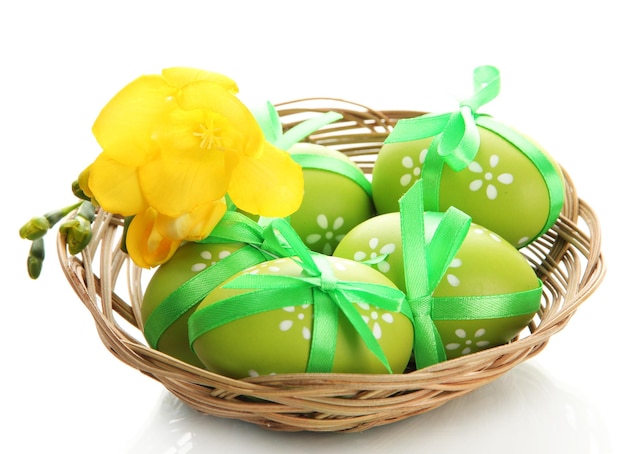 Oeufs de pâques lumineux avec des arcs dans le panier isolé sur blanc