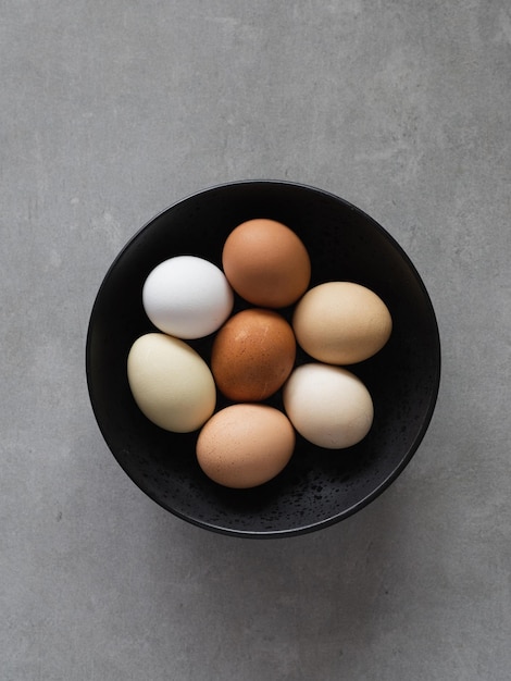 Oeufs de Pâques minimalistes Oeufs colorés par la nature sur une plaque noire sur fond gris Un oeuf de poule comme produit nutritif précieux Vue de dessus mise à plat