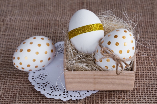 Oeufs de Pâques avec un motif doré dans une boîte de style rustique