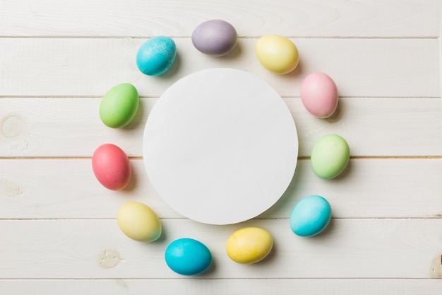 Oeufs de Pâques multicolores à cadre rond avec du papier blanc vierge sur un fond marron espace libre pour le texte vierge pour la conception image teintée de mise au point sélective