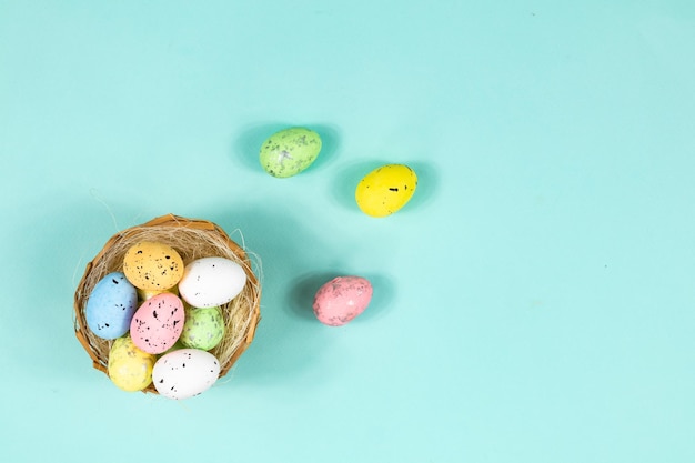 Oeufs de Pâques multicolores dans un nid sur un fond bleu avec un espace pour le lettrage de texte Base pour une carte postale Vue de dessus