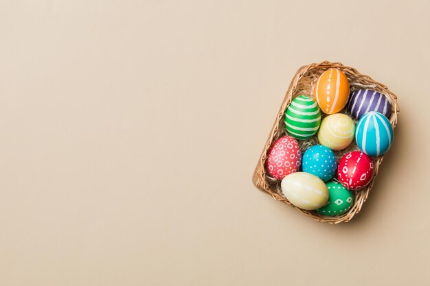 Oeufs de Pâques multicolores dans le panier tressé sur fond coloré Oeufs de Pâques de couleur pastel concept de vacances avec espace de copie