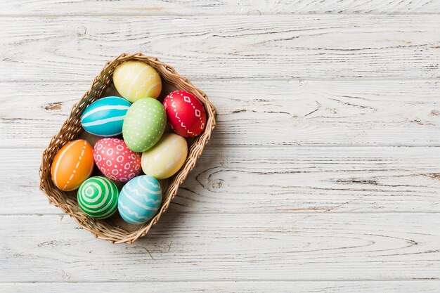 Oeufs de Pâques multicolores dans le panier tressé sur fond coloré Oeufs de Pâques de couleur pastel concept de vacances avec espace de copie