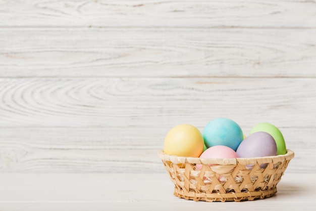 Oeufs de Pâques multicolores dans le panier tressé sur fond coloré Oeufs de Pâques de couleur pastel concept de vacances avec espace de copie