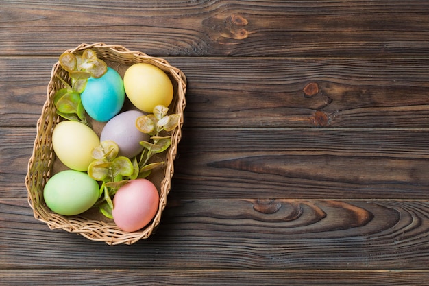 Oeufs de Pâques multicolores dans le panier tressé sur fond coloré Oeufs de Pâques de couleur pastel concept de vacances avec espace de copie