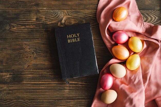 Oeufs de pâques multicolores et sainte bible sur fond de bois concepts religieux