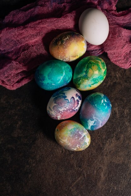 Oeufs de Pâques multicolores de tons bleus sur fond de tissu rose. Oeufs de Pâques en discret