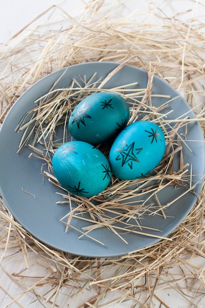 Oeufs de Pâques avec de la paille sur une plaque