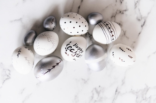 Oeufs de Pâques peints en argent et blanc sur fond de marbre carte postale espace libre pour le texte