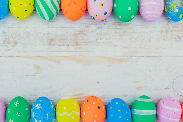 Oeufs de Pâques peints de couleurs pastel sur bois blanc.