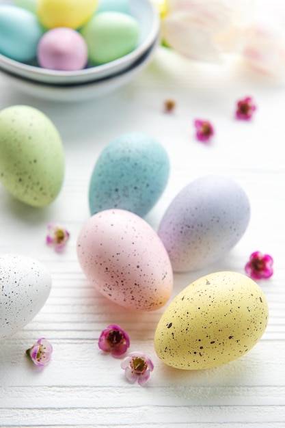 Oeufs de Pâques peints en couleurs pastel sur un fond en bois blanc