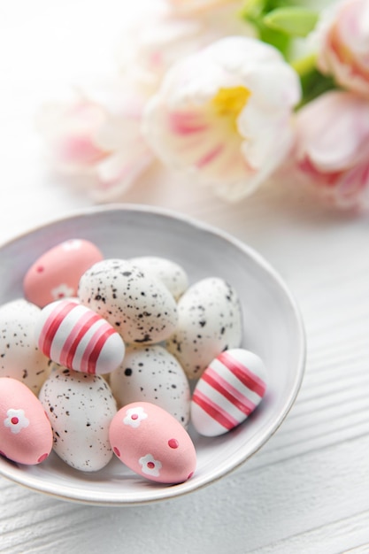 Oeufs de Pâques peints en couleurs pastel sur un fond en bois blanc