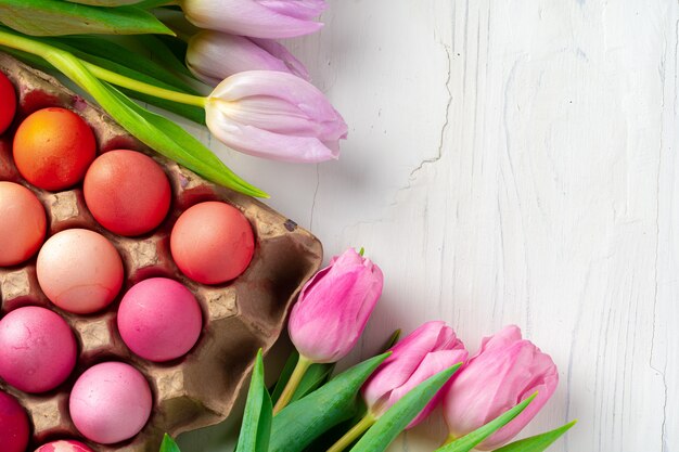 Oeufs de Pâques peints dans une boîte à oeufs avec des tulipes fraîches se bouchent