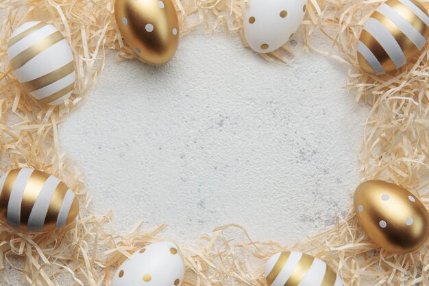 Oeufs de Pâques peints avec de la peinture dorée sur un fond de paille