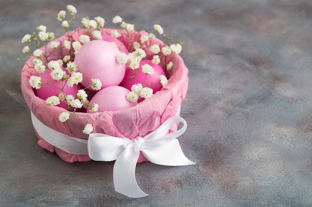 Oeufs de Pâques peints en rose dans un panier