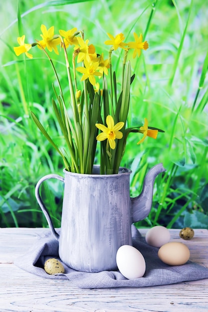 Oeufs de pâques pichet vintage en métal avec un bouquet de jonquilles jaunes en fleurs fraîches