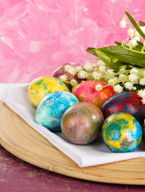 Oeufs de Pâques sur plaque de bois sur serviette avec gros plan de fleurs