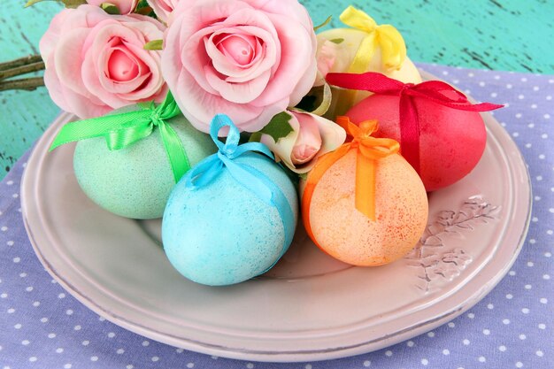 Oeufs de Pâques sur plaque avec serviette et fleurs sur table en bois