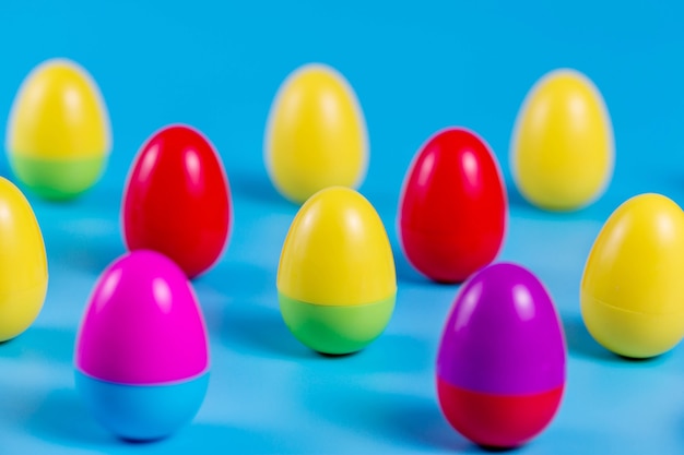 Oeufs de Pâques en plastique colorés sur fond bleu.