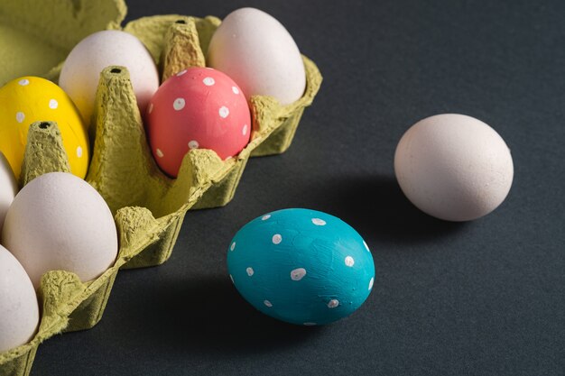 Oeufs de Pâques à pois colorés dans un plateau d'oeufs sur gris foncé noir