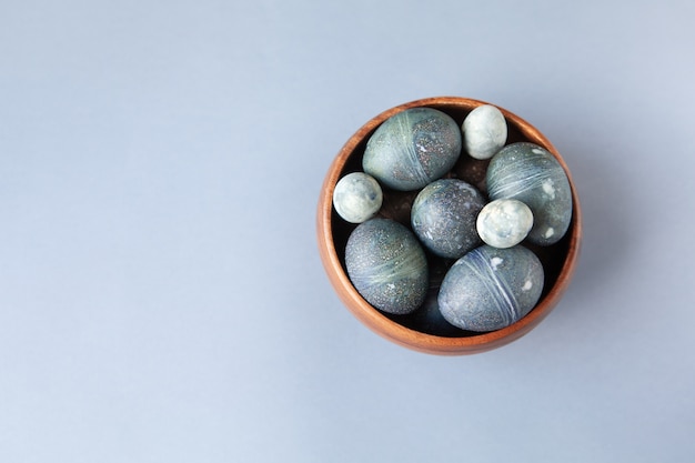 Oeufs de Pâques de poulet et de caille peints de manière créative avec un colorant d'hibiscus naturel, ressemblent à des pierres de mer dans un bol sur fond gris, copiez l'espace.