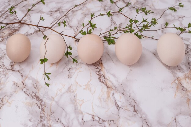 Oeufs de Pâques roses sur fond de marbre. brin de verdure. Lieu d'inscription. vue de dessus