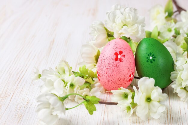 Oeufs de Pâques roses et verts dans un nid de paille et une branche