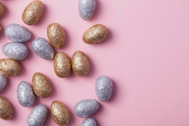 Oeufs de pâques scintillants d'or et d'argent sur fond rose pastel