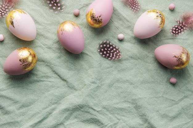 Les oeufs de Pâques sont peints avec de la peinture violette et verte sur un fond de lin gris