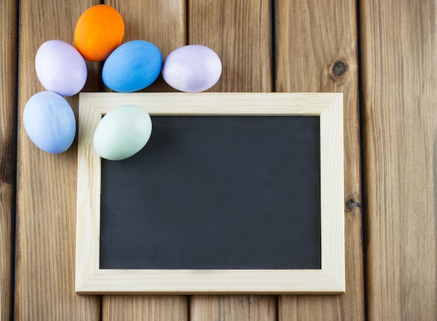 Oeufs de pâques sur un tableau noir avec un tableau noir sur le bois