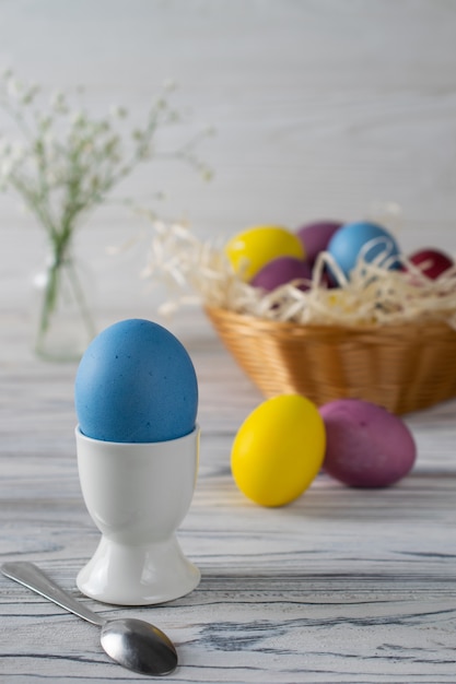 Oeufs de Pâques teints colorés dans un panier avec oeuf bleu dans une tasse