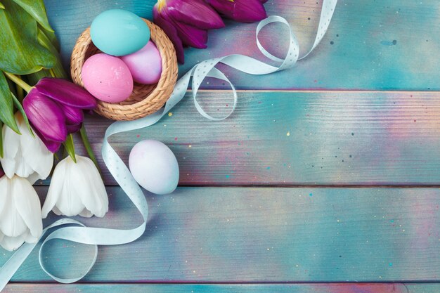 Oeufs de Pâques avec des tulipes sur bois bleu