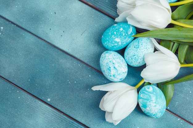 Oeufs de Pâques avec des tulipes sur bois bleu