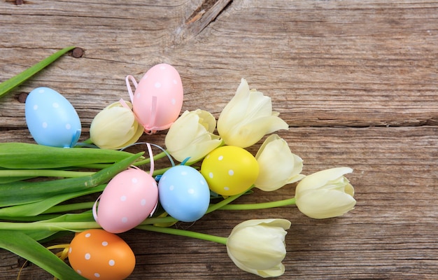 Oeufs de Pâques et tulipes sur fond de bois et espace de copie