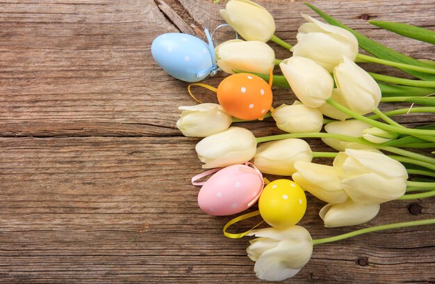 Oeufs de Pâques et tulipes sur fond de bois et espace de copie