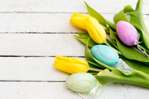 Oeufs de Pâques et tulipes fraîches de printemps sur une table en bois patiné