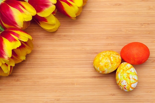 Oeufs de Pâques avec des tulipes sur une planche de bois, concept de vacances de Pâques. Fond