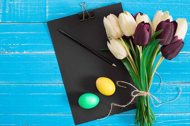 Oeufs de Pâques et tulipes sur des planches de bois bleues