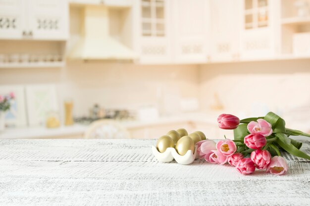 Oeufs de Pâques, tulipes sur table en bois blanc de cuisine. Composition de printemps. Espace pour le design.