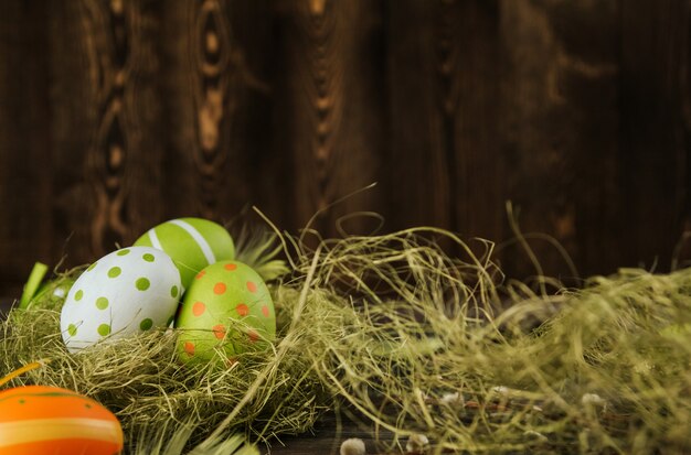 Oeufs de Pâques verts et orange dans un nid de sisal sur un espace de copie de fond en bois. Oeufs peints