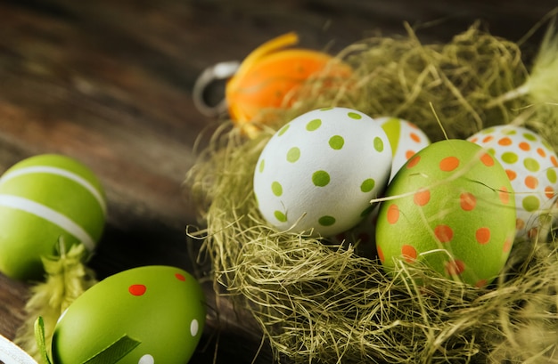 Oeufs de Pâques verts et orange dans un nid de sisal sur un espace de copie de surface en bois. Oeufs peints